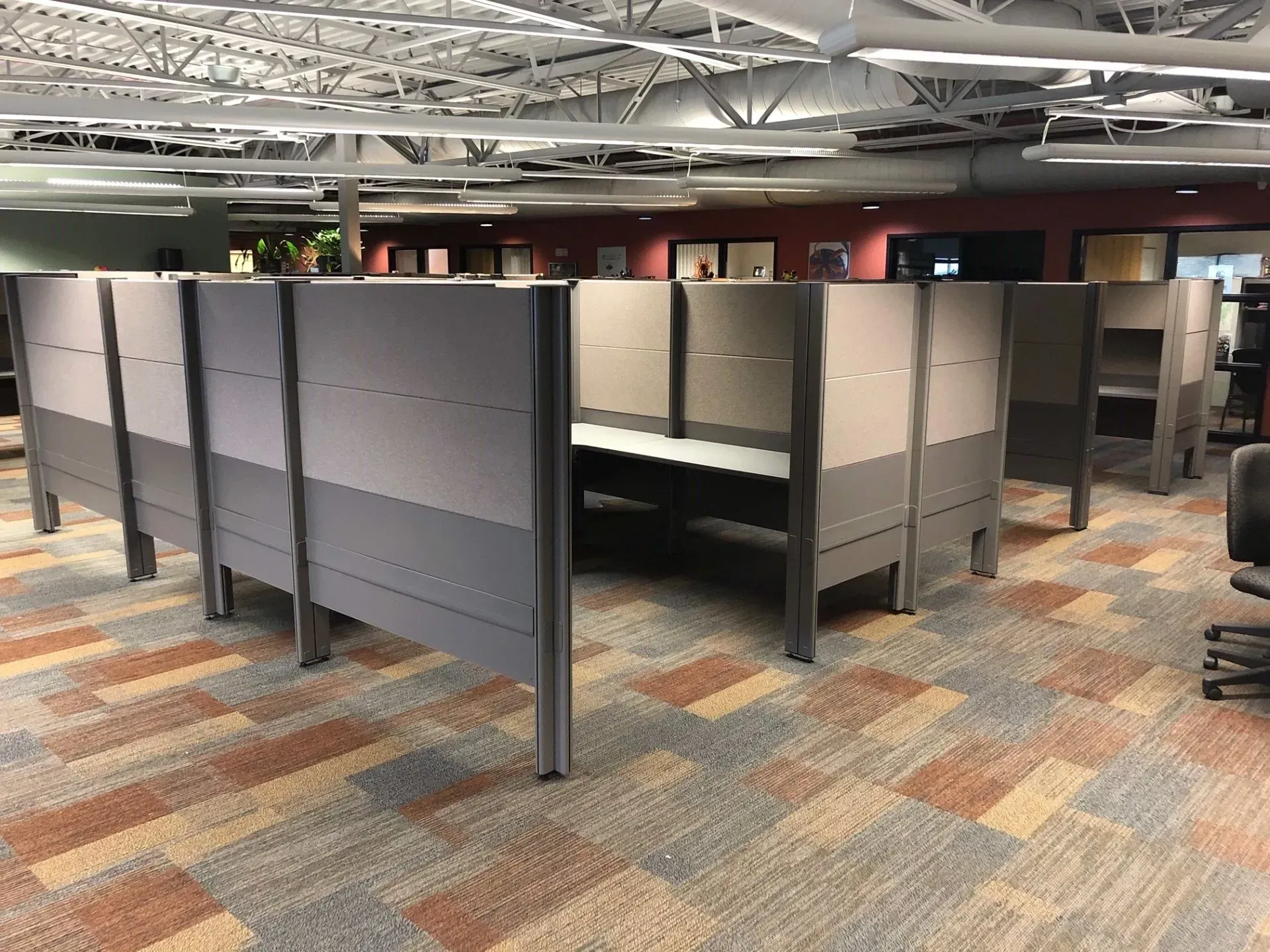 Office cubicles with gray partitions in an open workspace under exposed ceiling beams