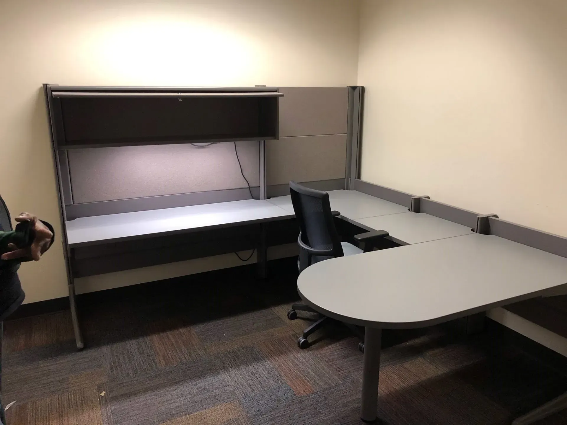 Empty office cubicle with desk, chair, and gray partition walls