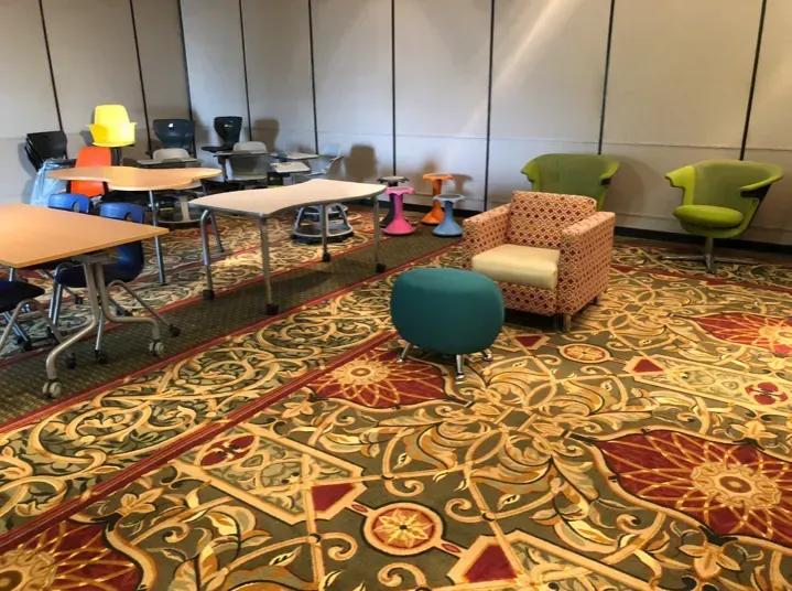 Conference room with tables, colorful chairs, and patterned carpet.