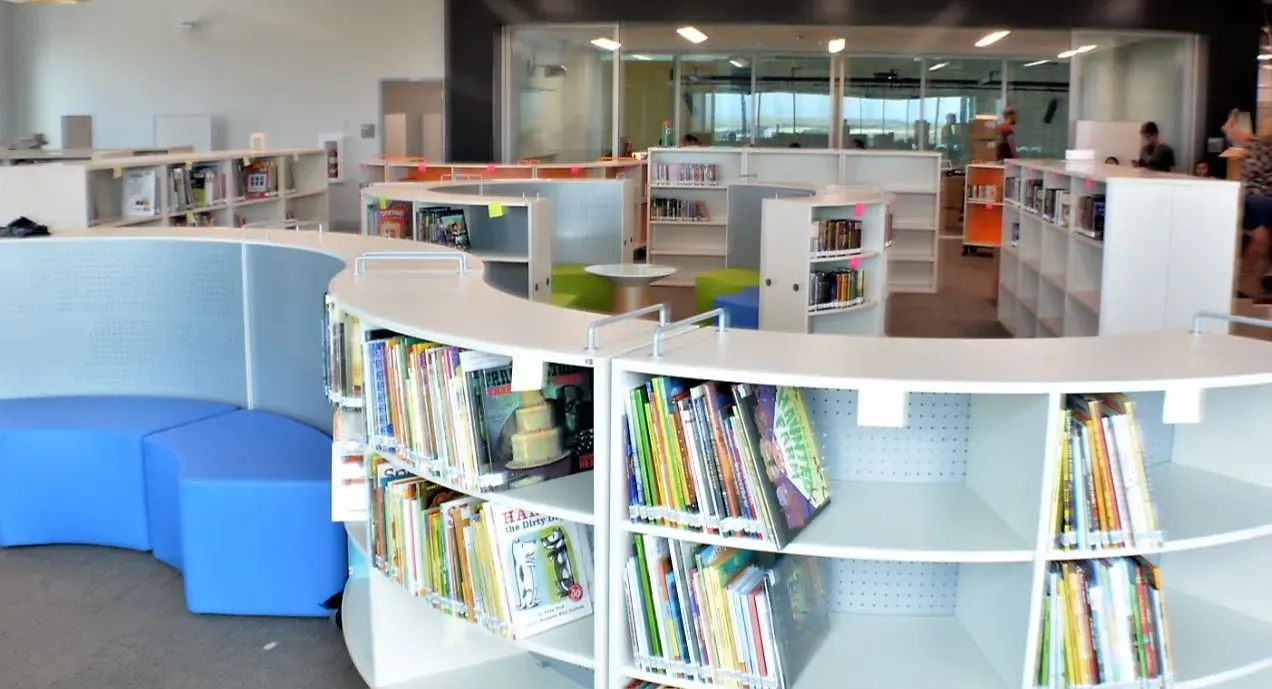 Modern library with curved blue seating and low bookshelves in a bright open reading area