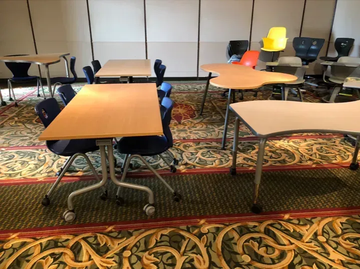 Empty conference room with several tables and chairs on a patterned carpet