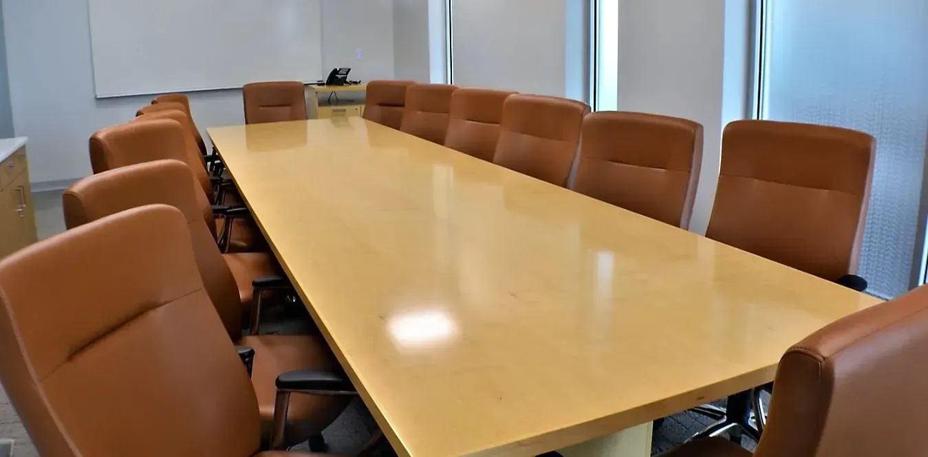 Empty conference room with a long wooden table and brown leather chairs
