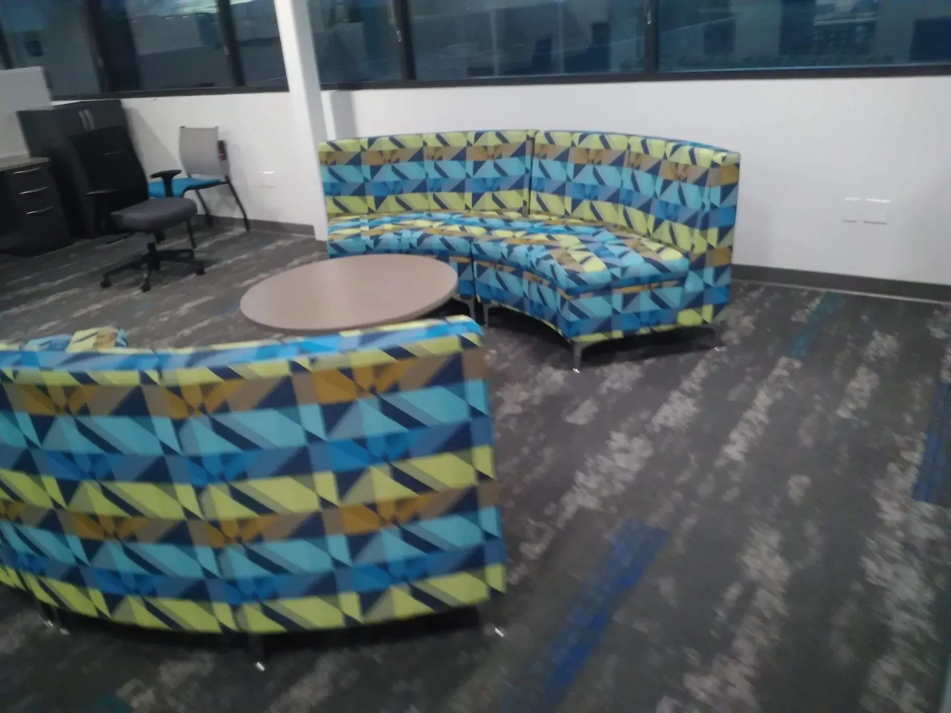 Waiting area with colorful geometric lounge chairs and round tables on a carpeted office floor