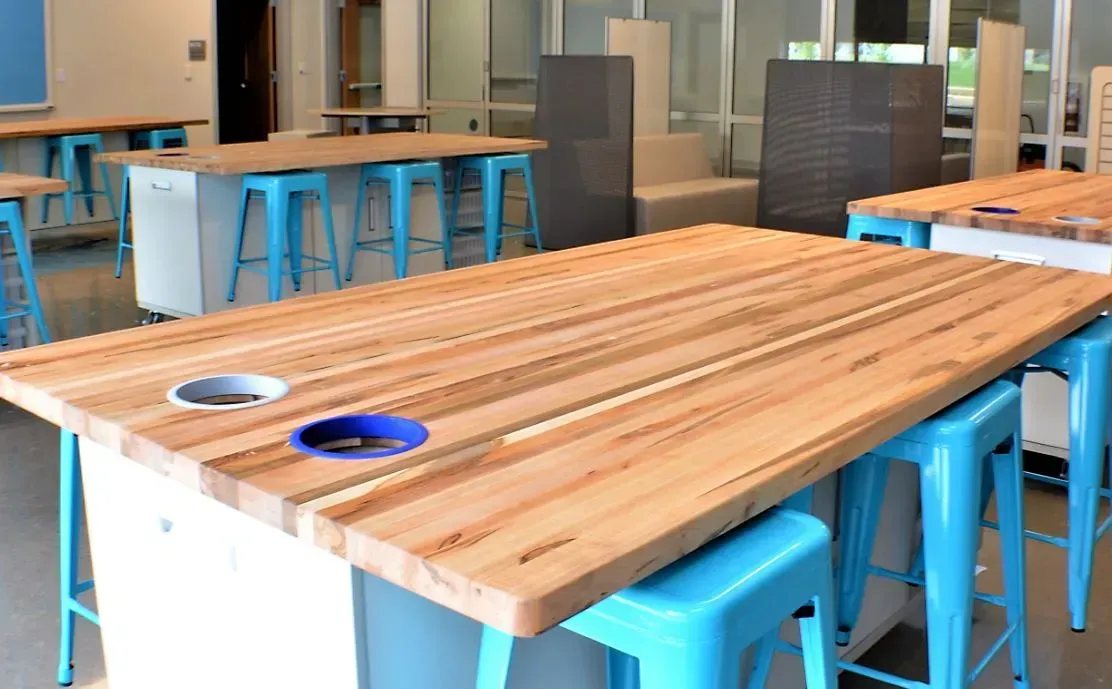 Modern meeting room with a large wooden table and bright blue stools