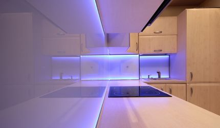 a kitchen with purple lights on the walls and a stove top oven .