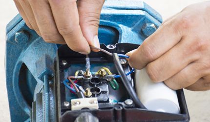 A person is fixing generator wires with a screwdriver