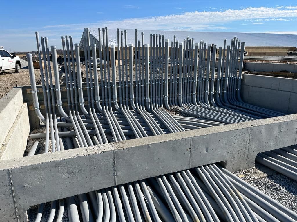 A bunch of metal pipes are stacked on top of each other on a construction site.