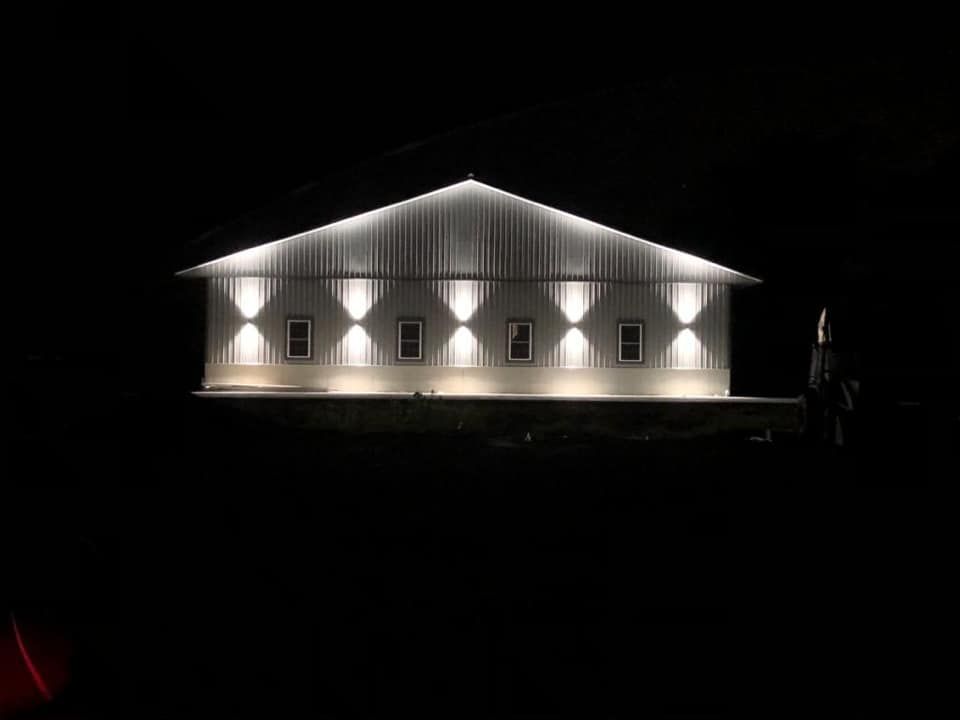 A large white barn is lit up at night.