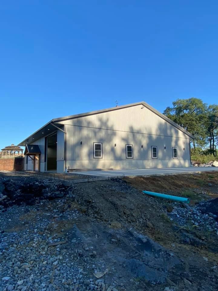 A large white building is sitting in the middle of a dirt field.