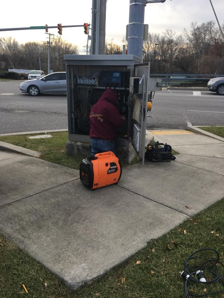 A man is working on an electrical box on the sidewalk.