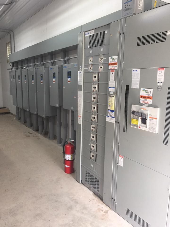 A fire extinguisher is sitting next to a row of electrical panels.