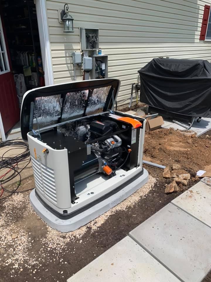 A generator is sitting in the dirt in front of a house.