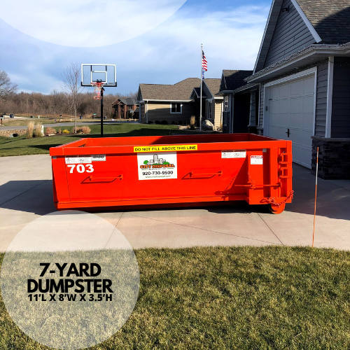 A large orange dumpster is parked in front of a house.