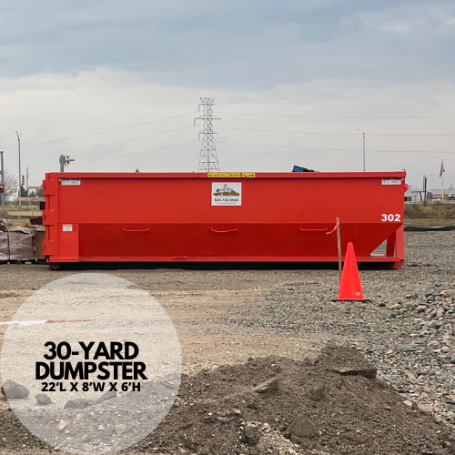 A large orange dumpster is parked in front of a building.