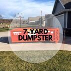 A 7 yard dumpster is parked in front of a house.