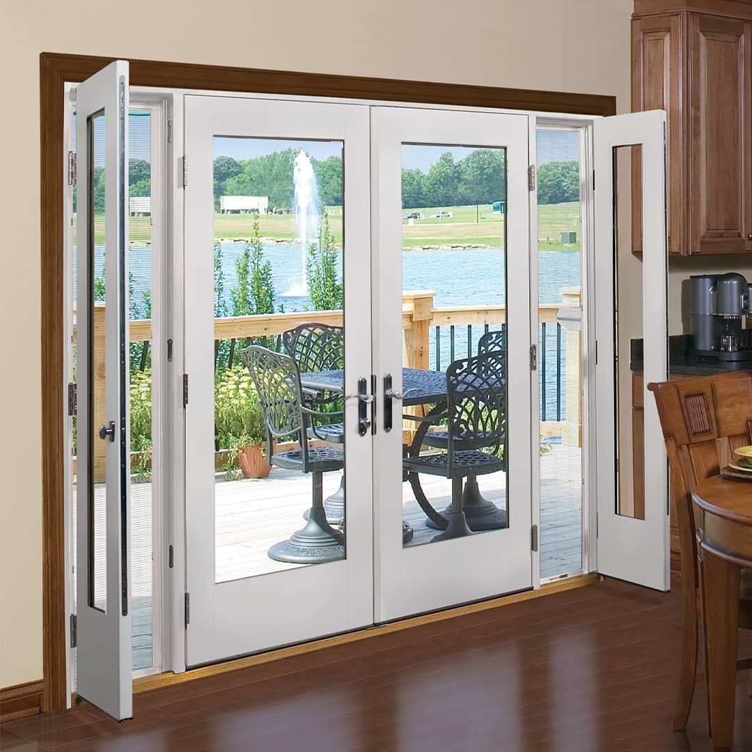 White, multi-pane folding patio doors open to a lake and deck.