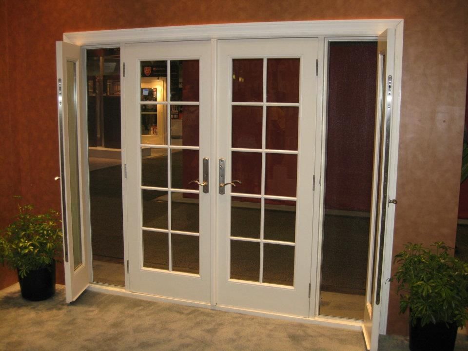 White French doors with multiple glass panes; two potted plants frame the entrance.
