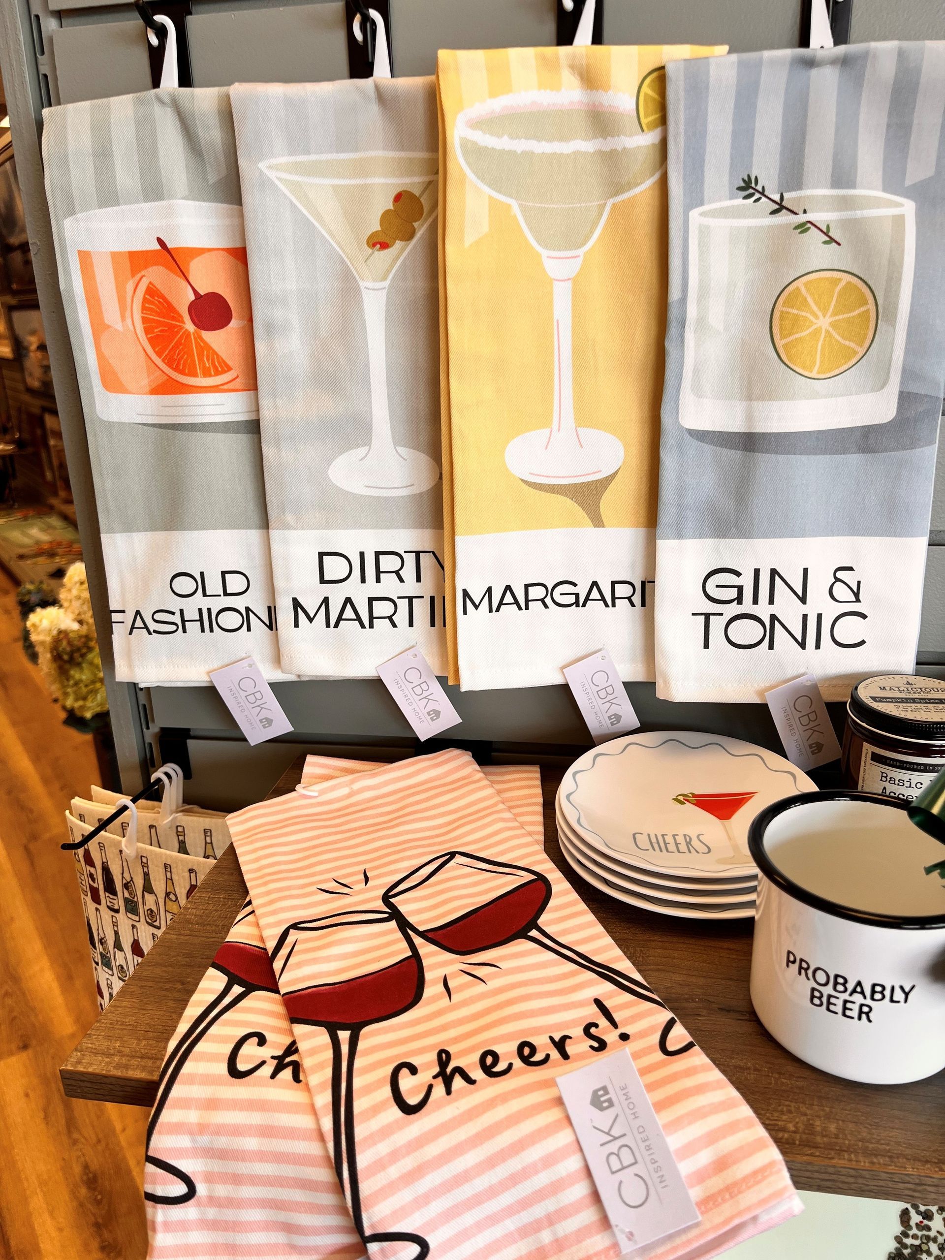 Cocktail-themed gift display with martini, margarita, and gin tonic designs, plus cheers coasters and napkins.