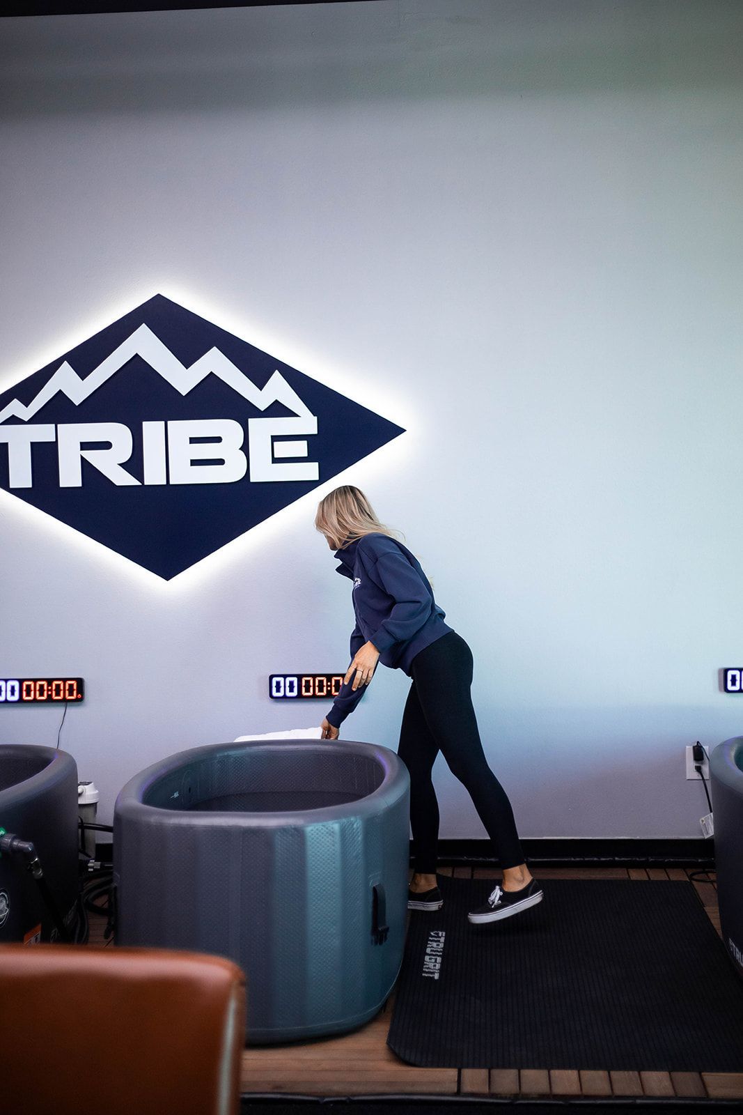 Woman next to an ice bath tub, reaching for something. 