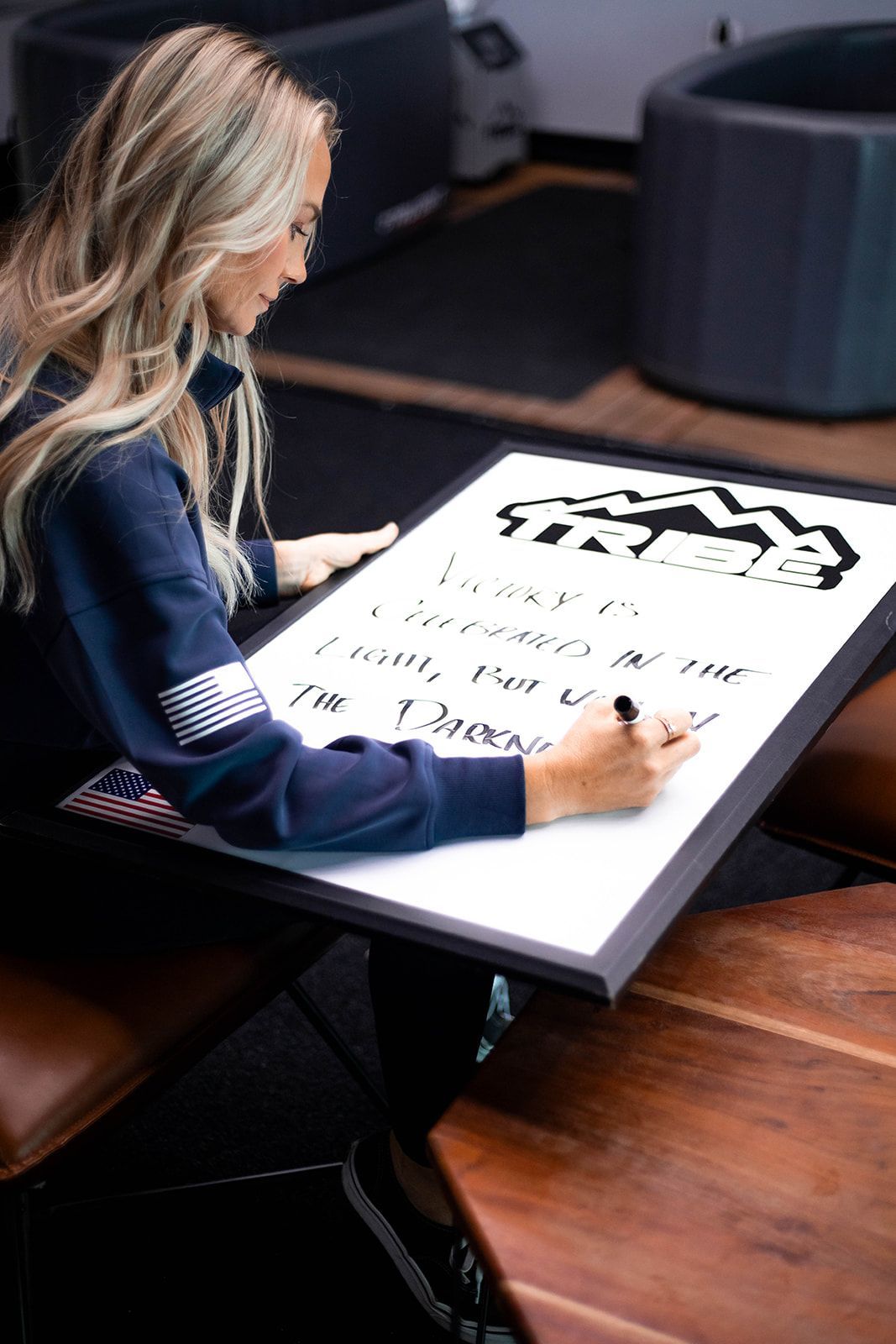 Woman in blue writes on large white sign.
