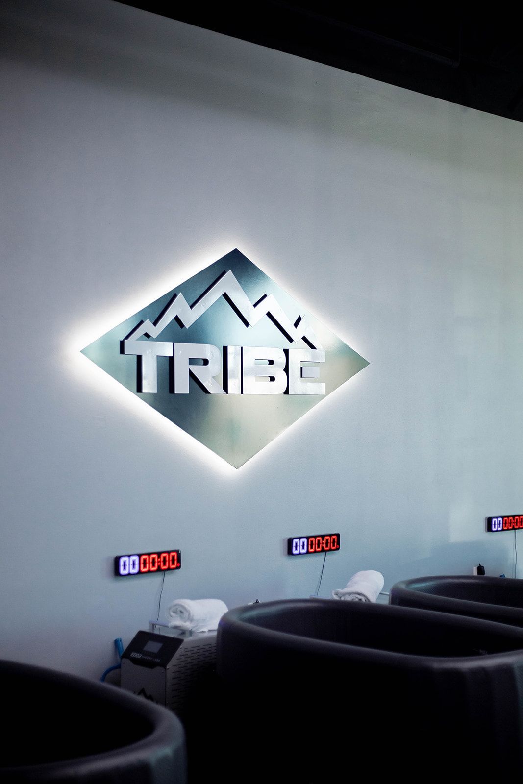 Silver Tribe logo with mountains on a wall, above three dark tubs and digital timers.