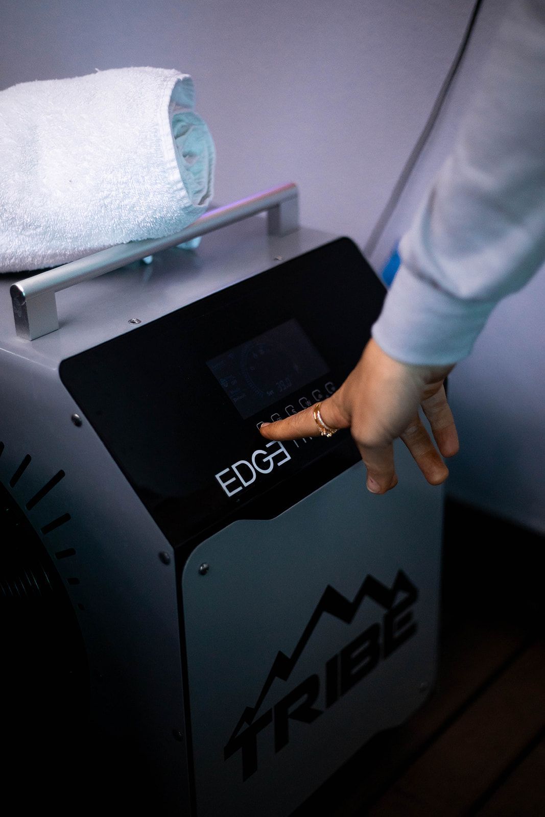 Person's finger pressing a button on a black and silver machine labeled 