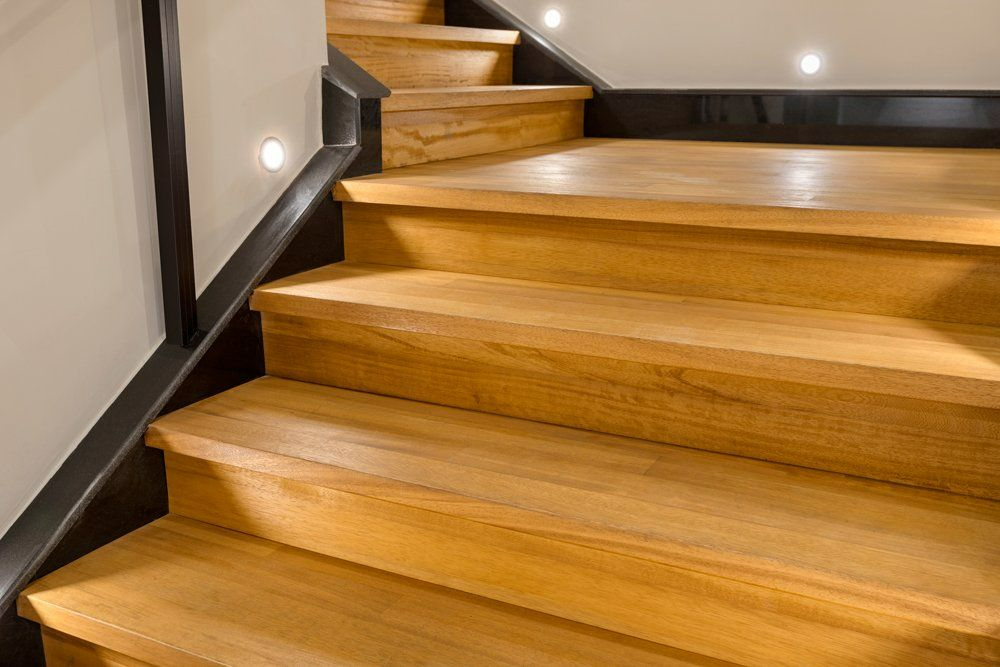 A close up of a wooden staircase with a black railing.