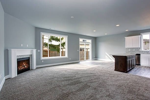 An empty living room with a fireplace and a large window.