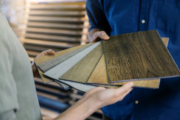 A man and a woman are holding a stack of wooden samples.