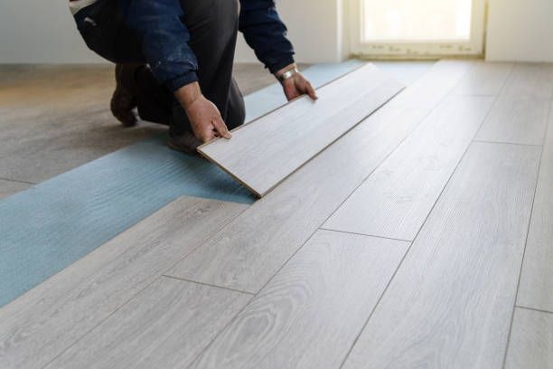 A person is installing a wooden floor in a room.