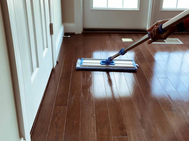 A person is mopping a wooden floor with a mop.