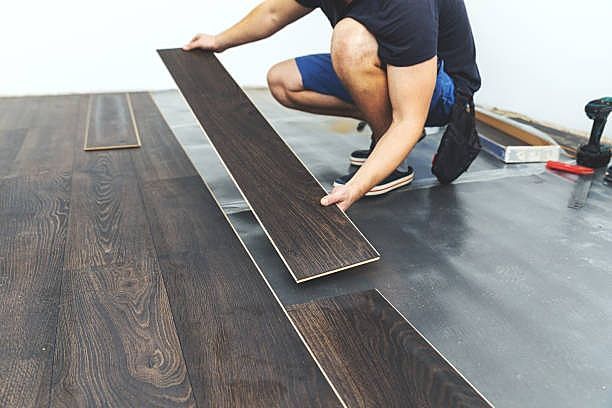A man is installing a wooden floor in a room.
