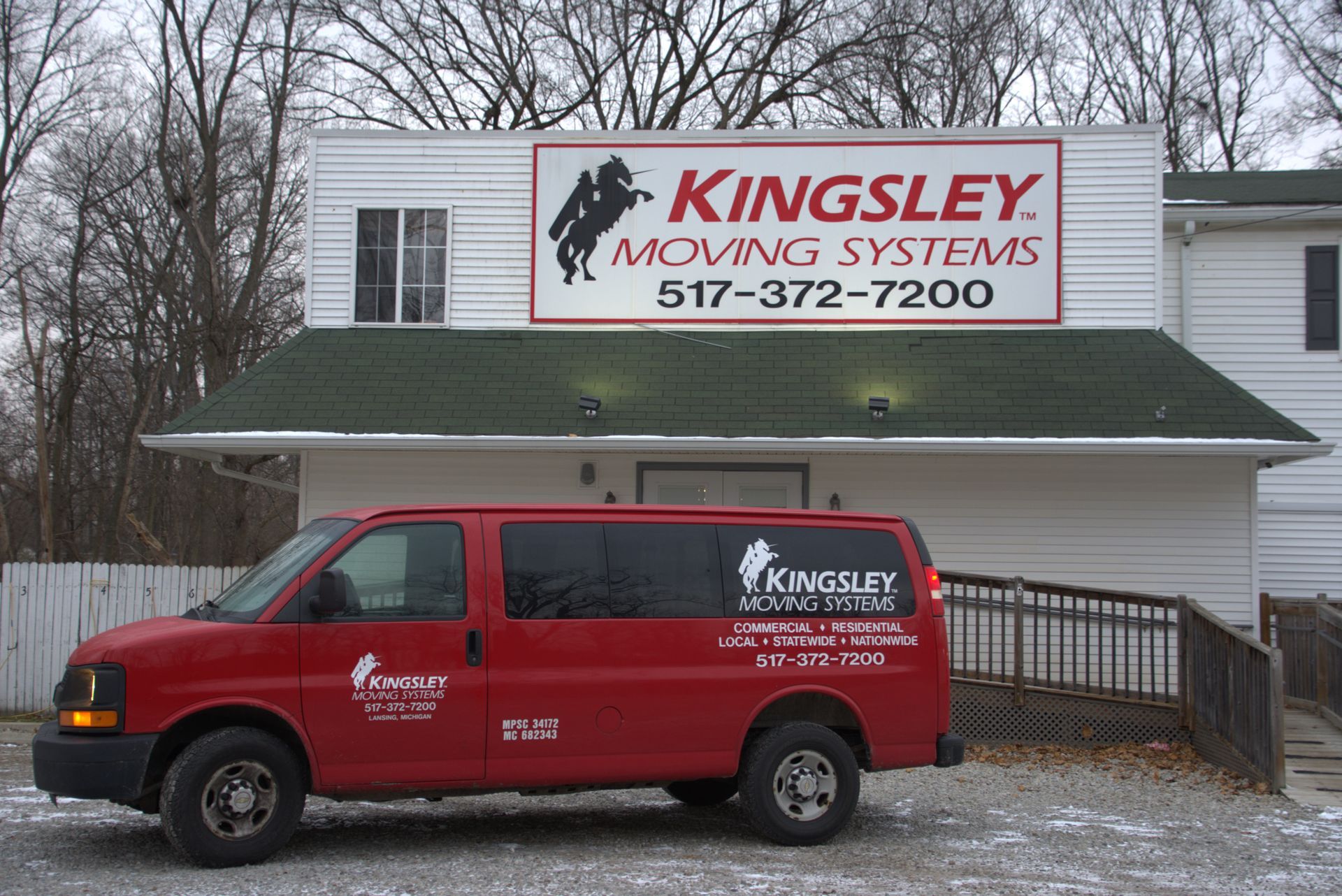 Red Kingsley Moving Systems van parked in front of a white building with a large company sign.
