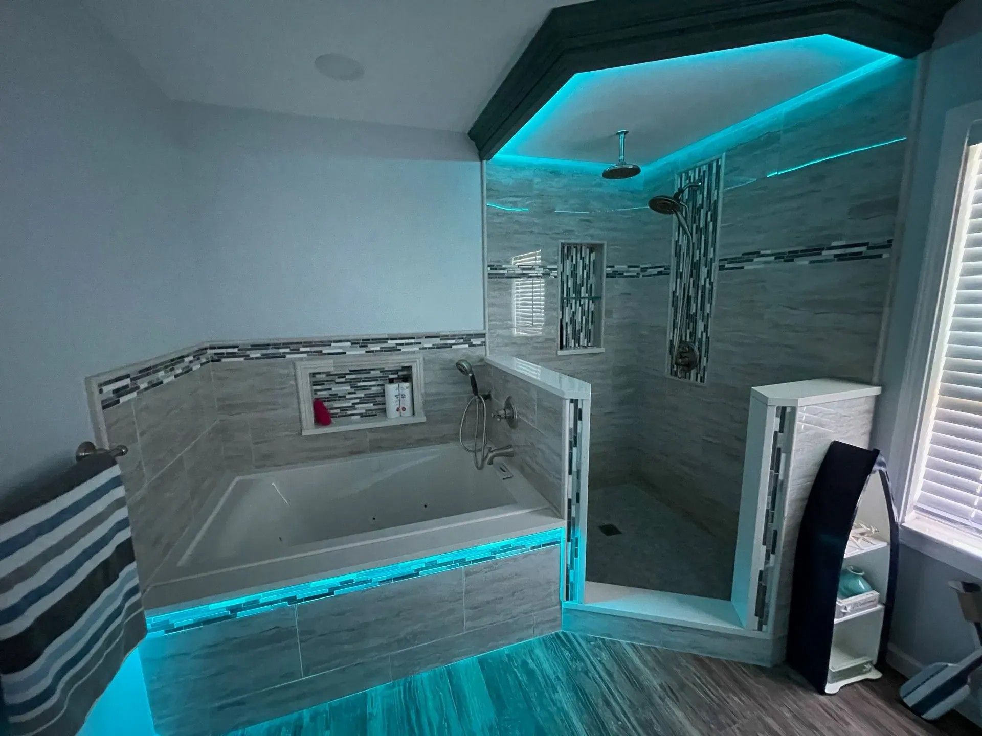 Bathroom with tub, shower, and blue LED lighting accents