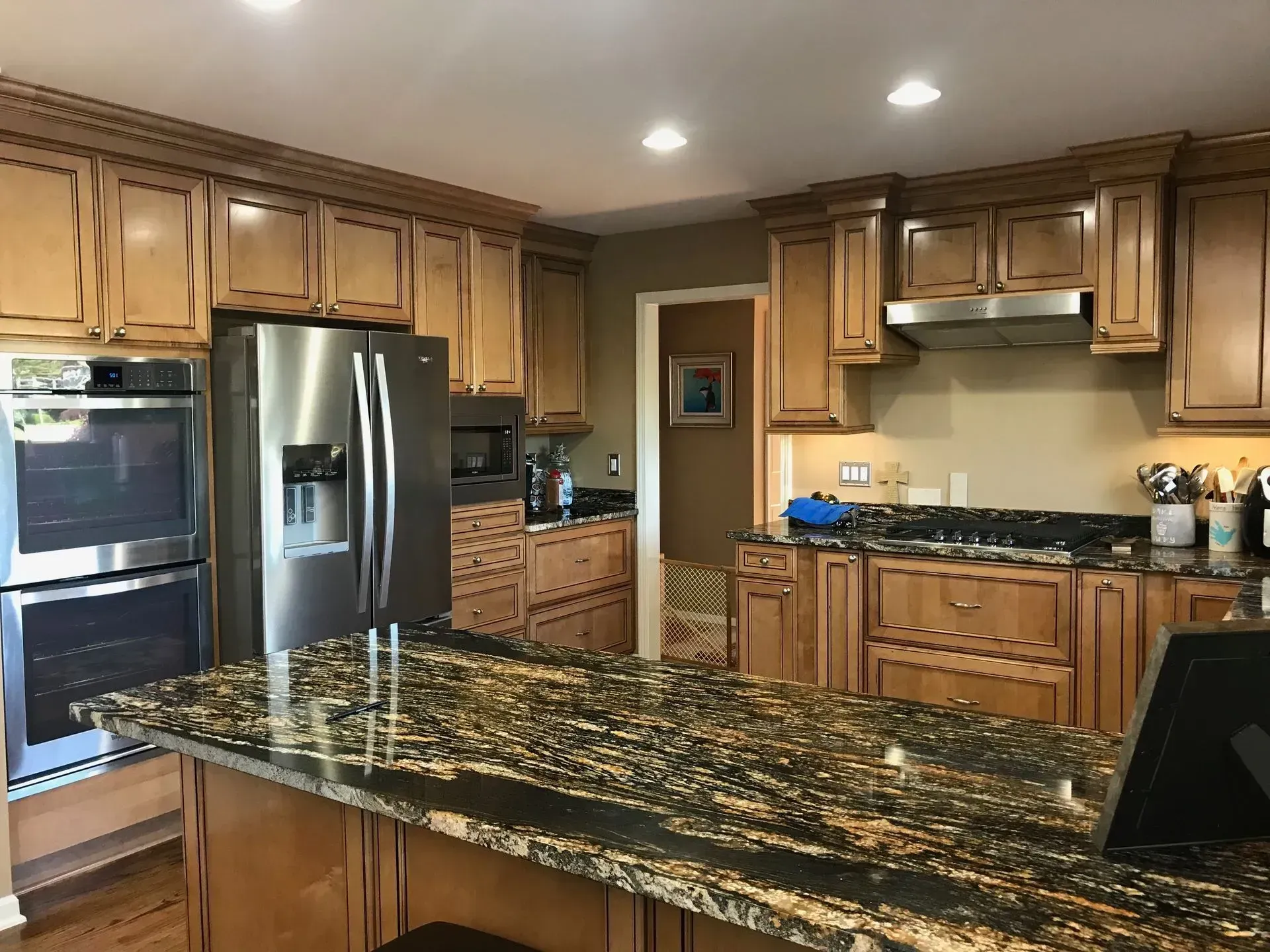 Kitchen with granite island, stainless steel appliances, and light wood cabinets.