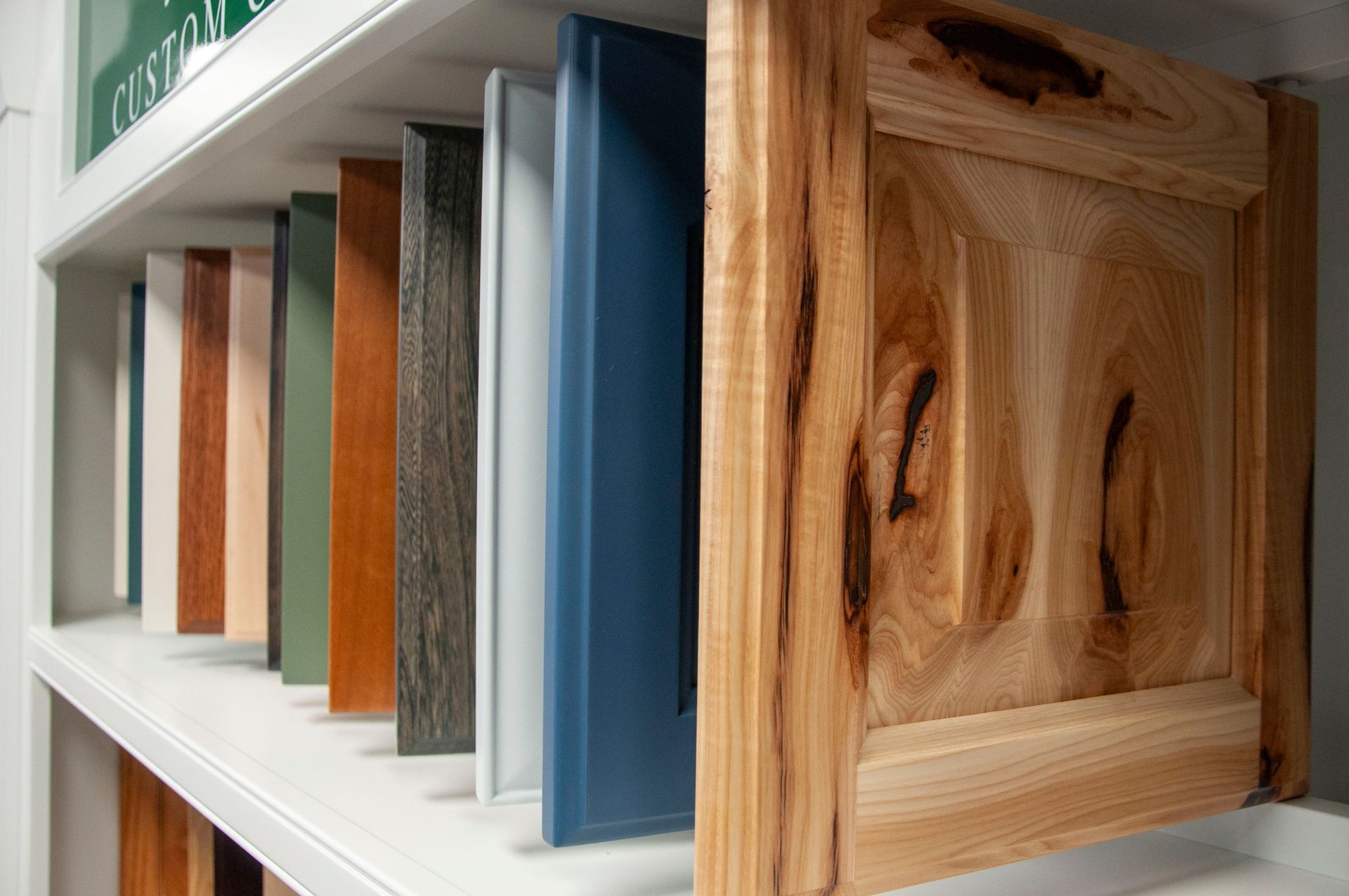 Shelf of colorful cabinet door samples, including wood grain and painted options.