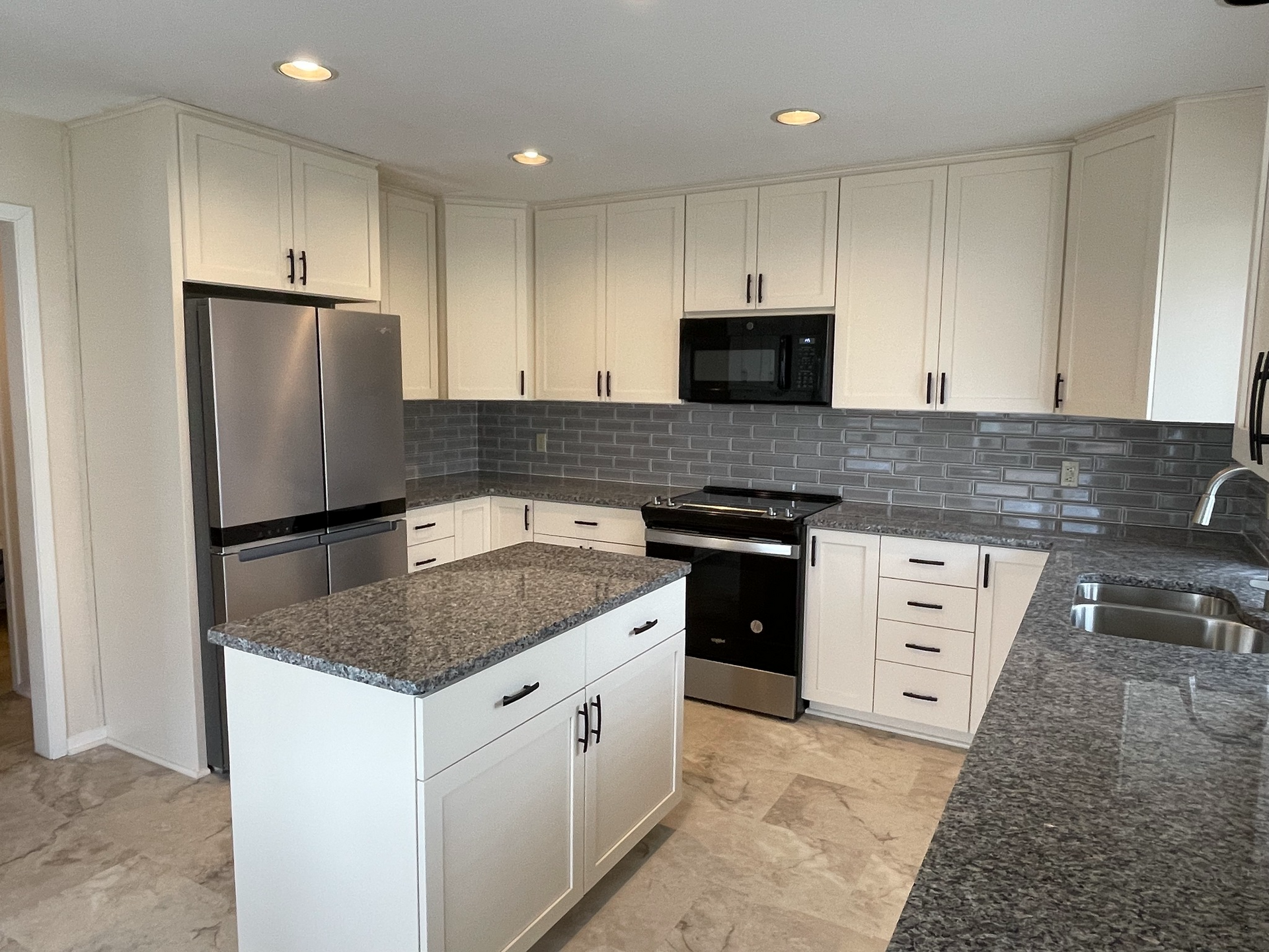 Modern kitchen with white cabinets, granite countertops, and stainless steel appliances.