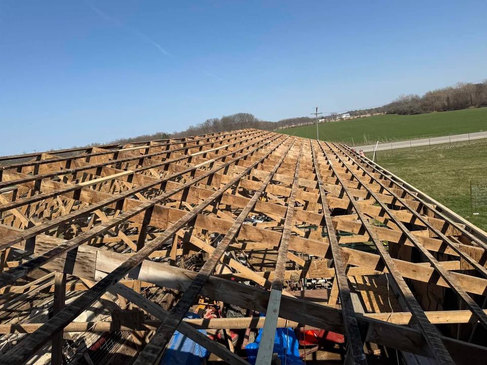 Wooden roof structure framework under a clear blue sky, open for renovation.