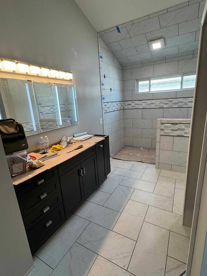 Bathroom with black vanity, tiled shower, and light gray walls; under construction.