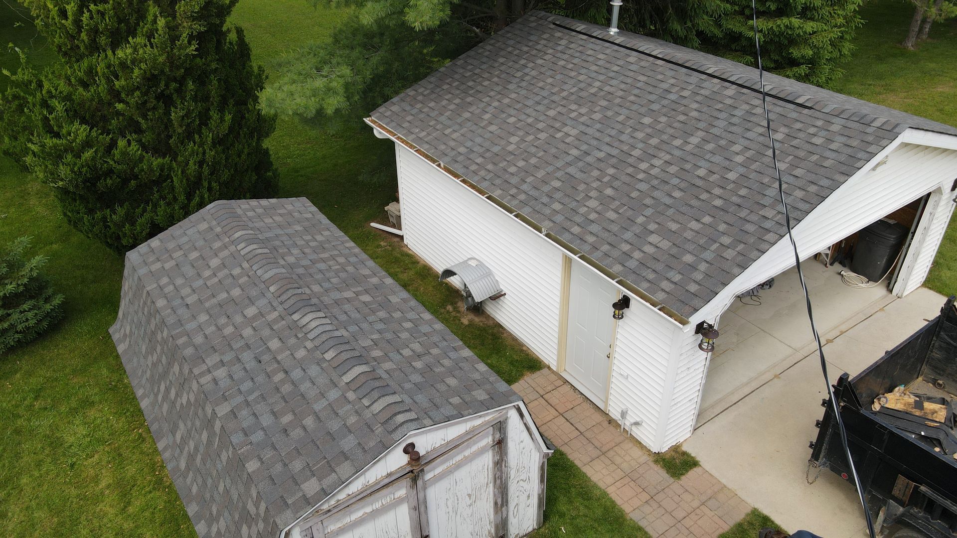 Overhead view of two white buildings with grey shingle roofs, on a green lawn.