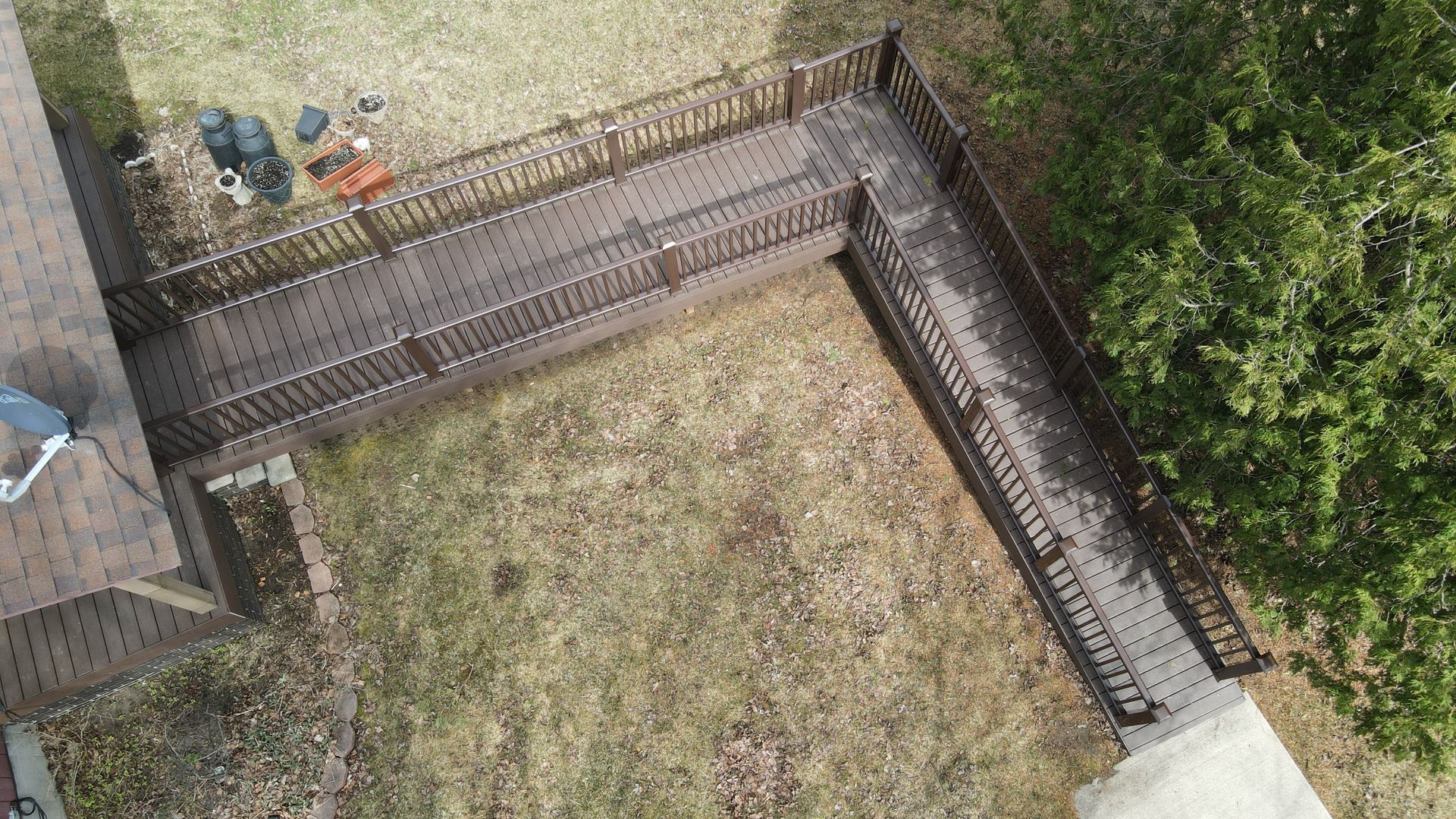 Wooden ramp with railings extends from a house, crossing a grassy yard.