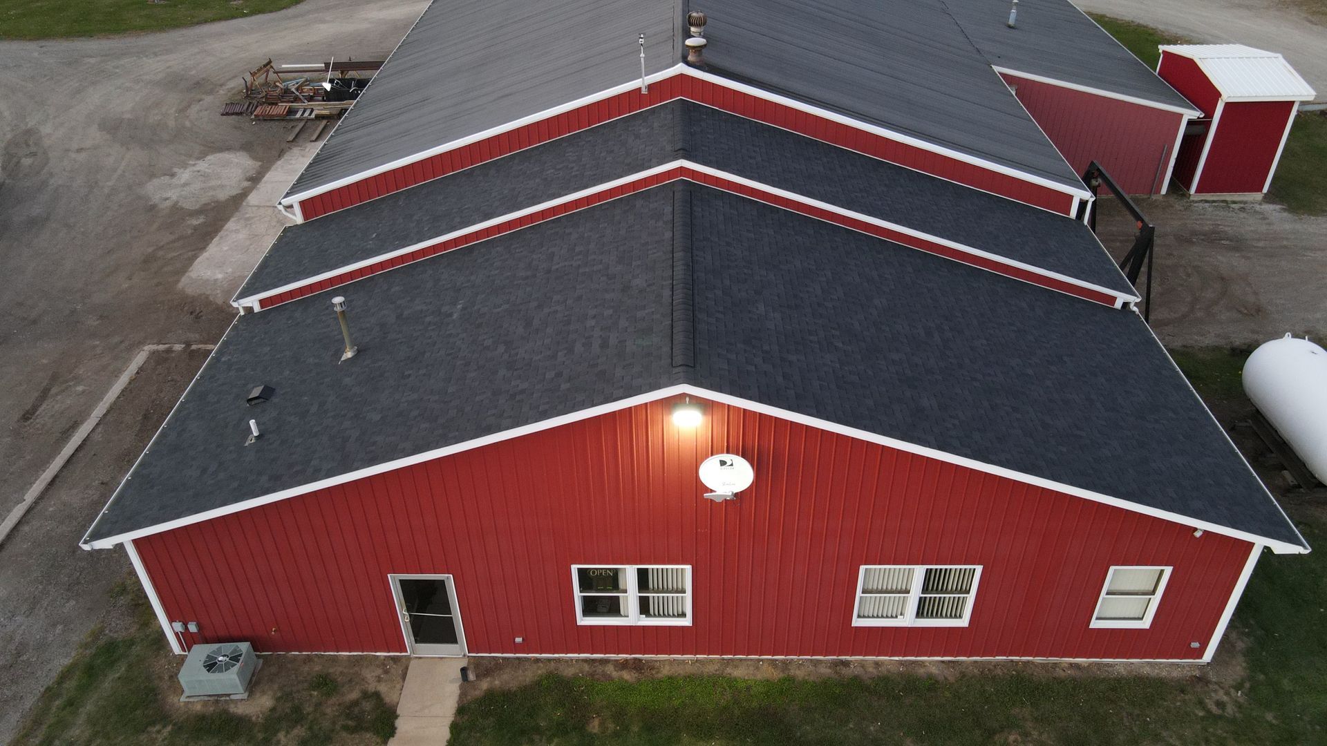 Red barn with white trim and dark gray roof.  Two windows and a door visible.