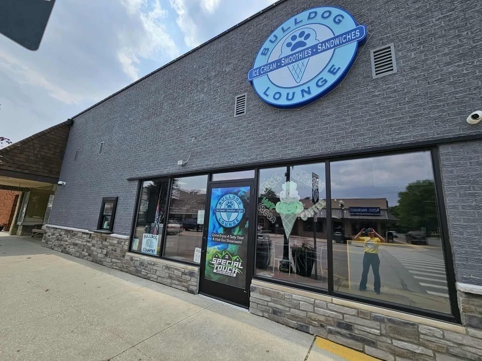 Bulldog Lounge ice cream shop exterior with blue logo, gray building, and large windows.