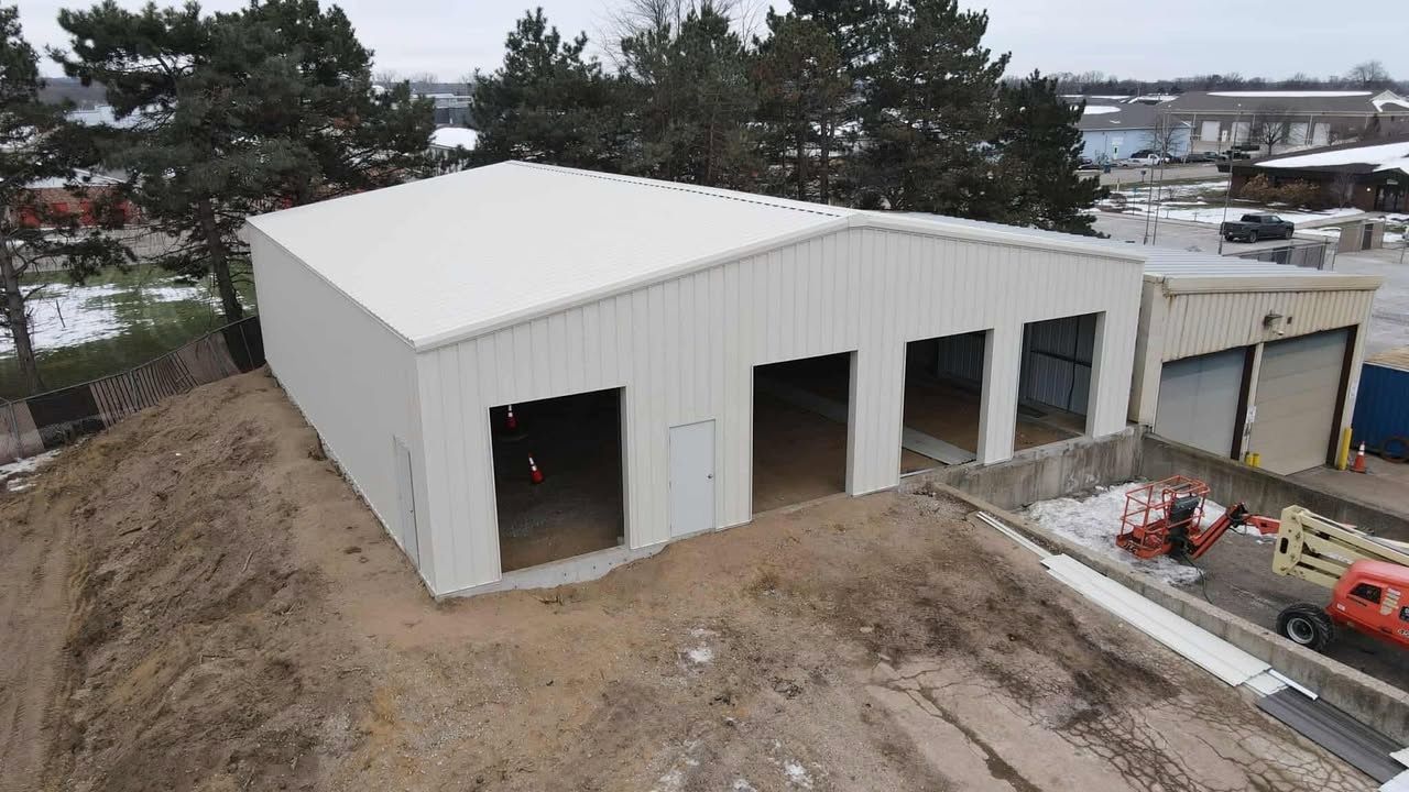 White metal building with open bays, on a dirt mound.