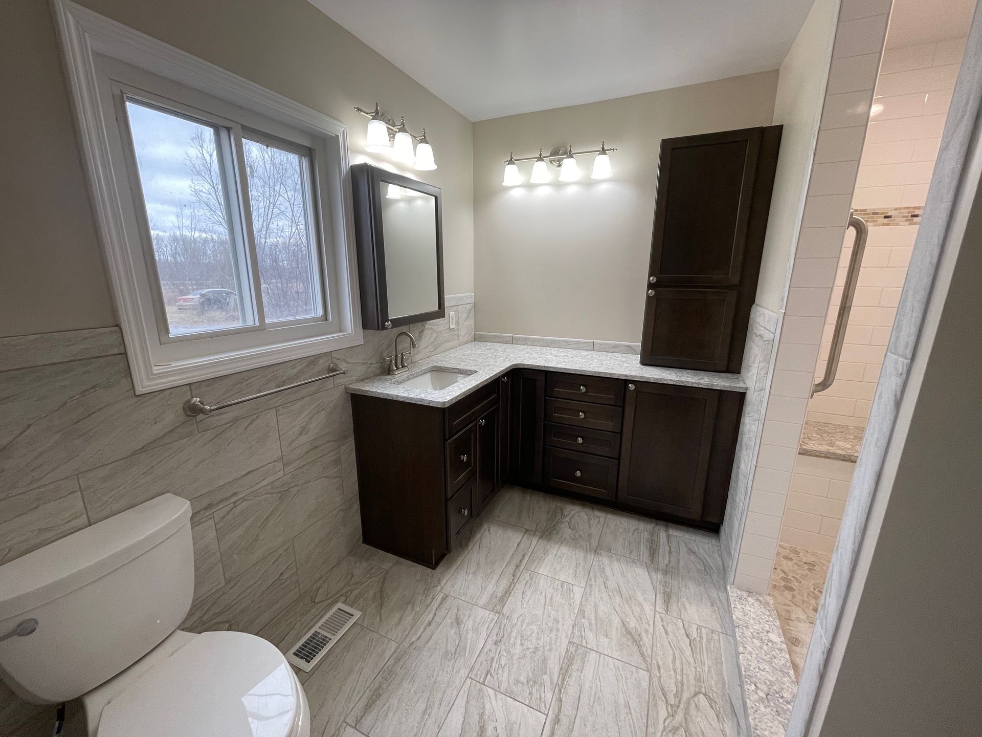 Bathroom with dark brown cabinetry, white countertop, and gray tiled floor.
