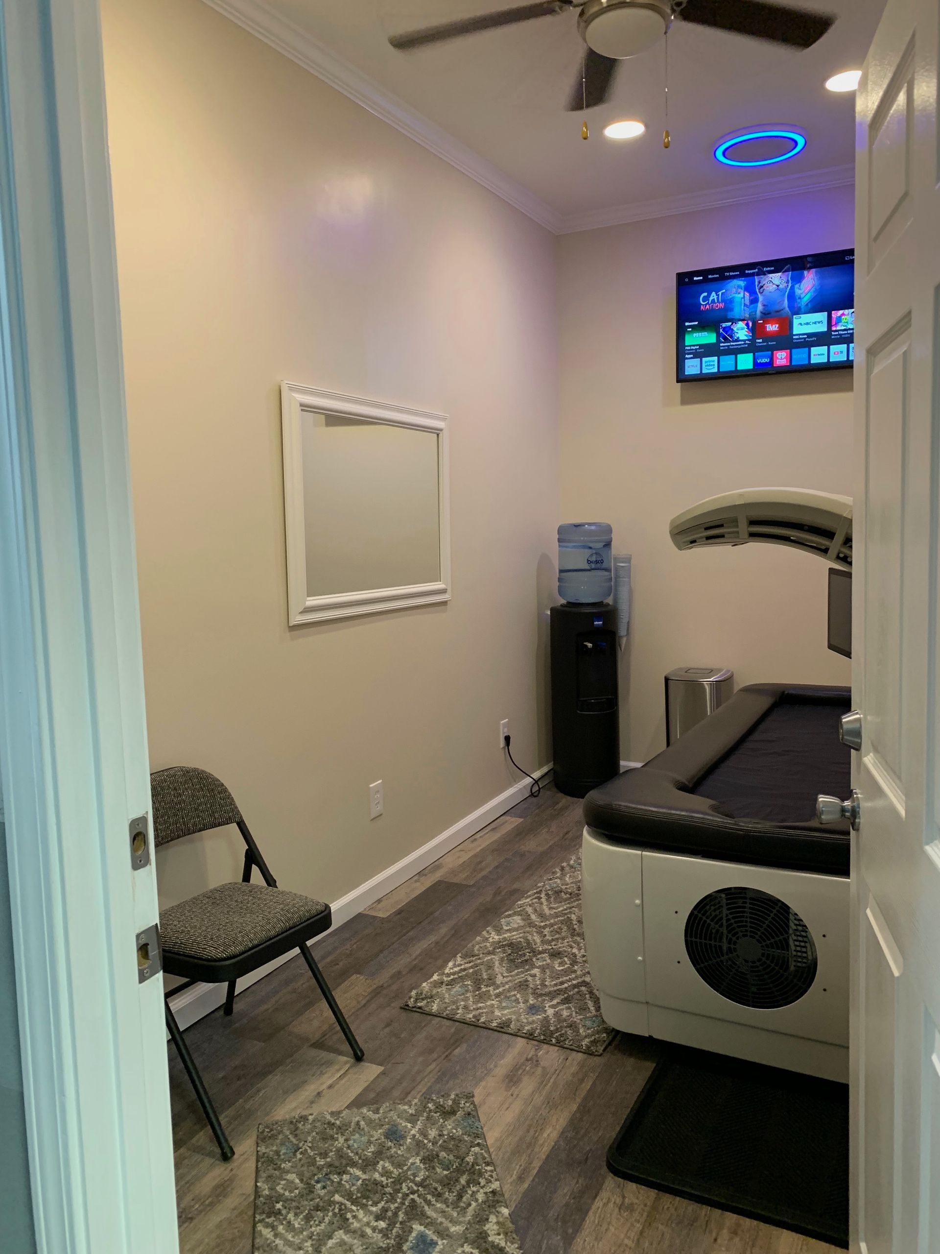 Small room with a pool table, TV, water cooler, chair, and mirror.