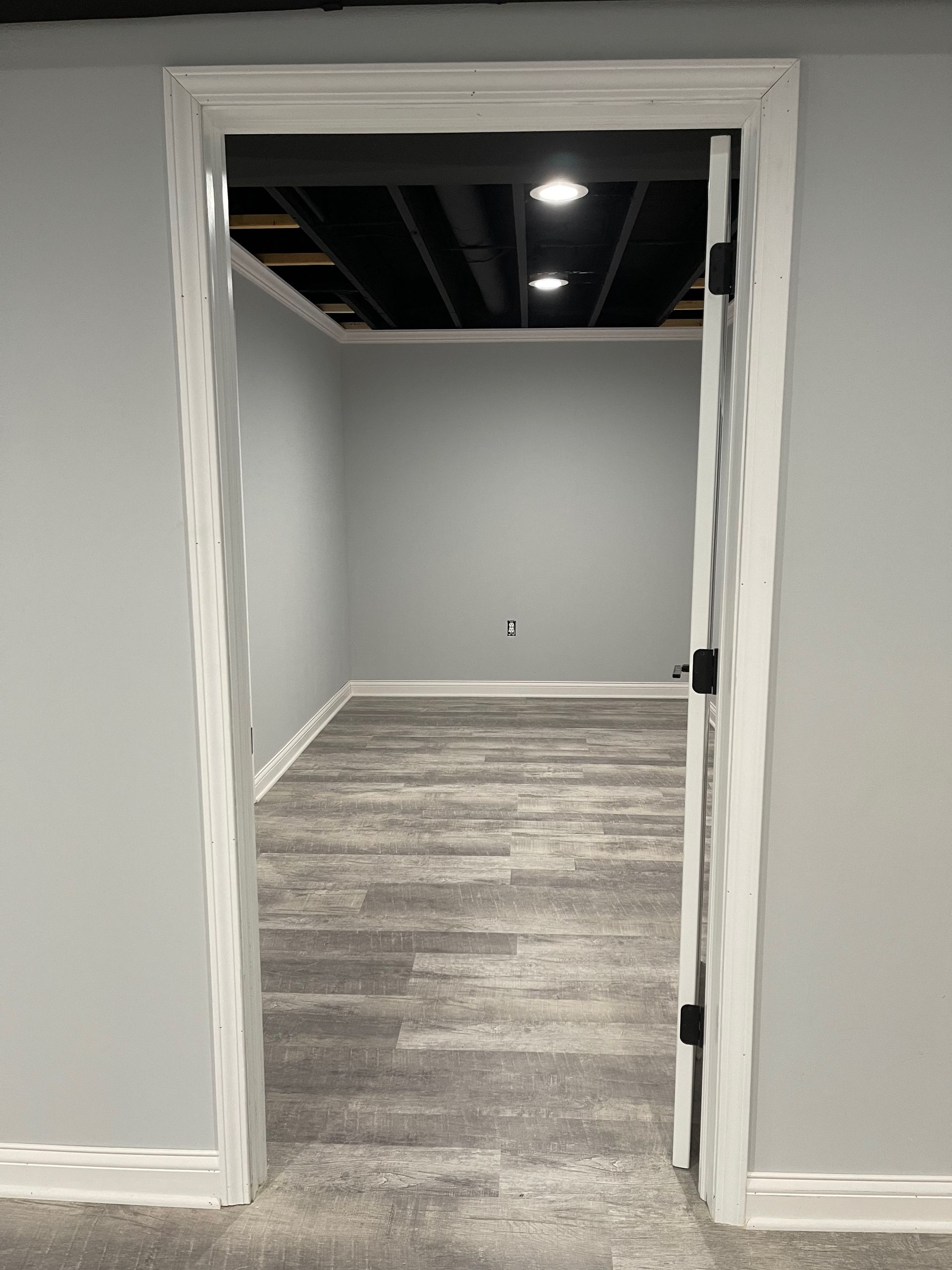 Doorway into a finished room with gray walls, wood-look flooring, and recessed lighting.
