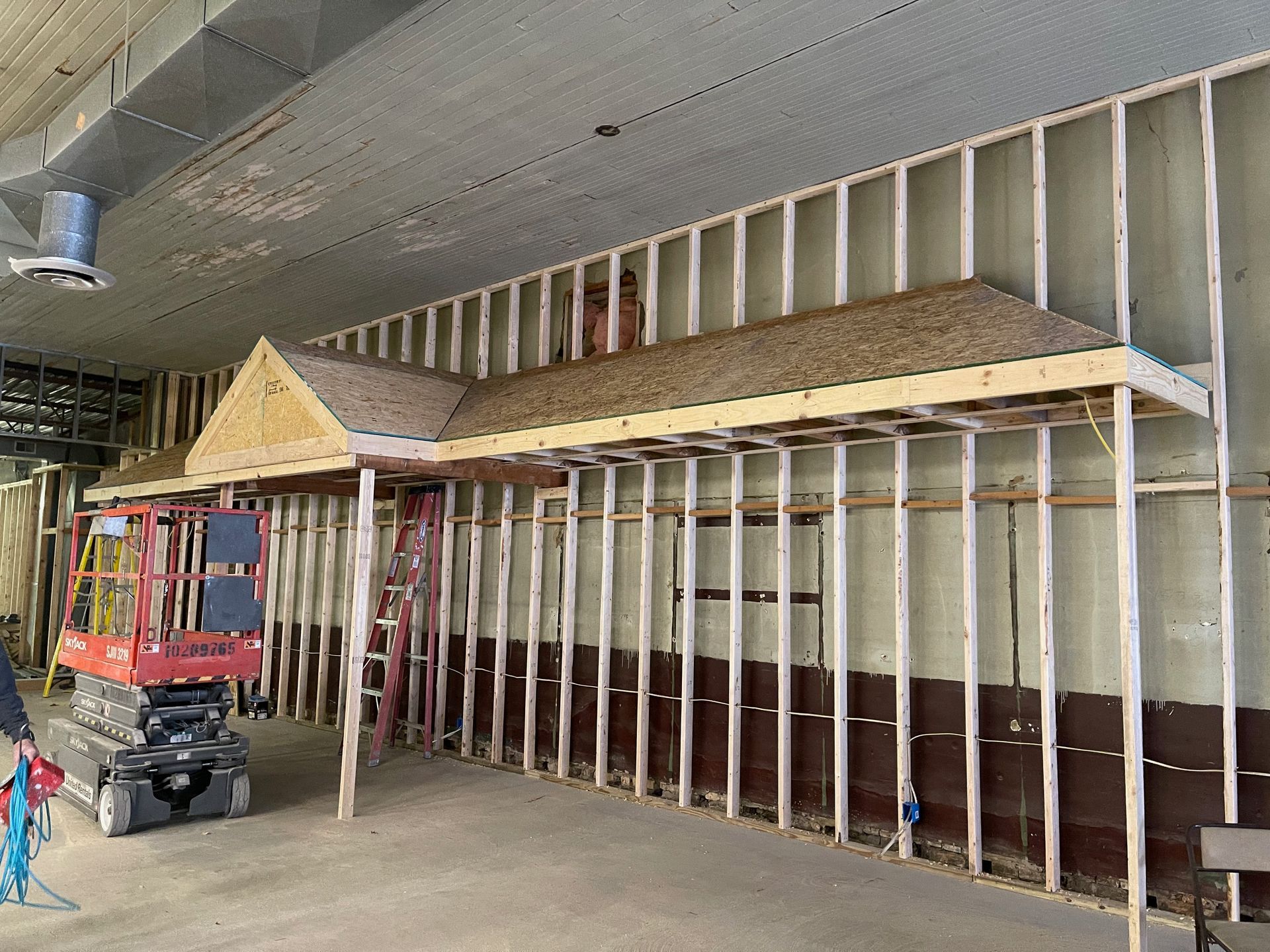 Construction of a building interior. Wooden wall framing with a small roof structure.