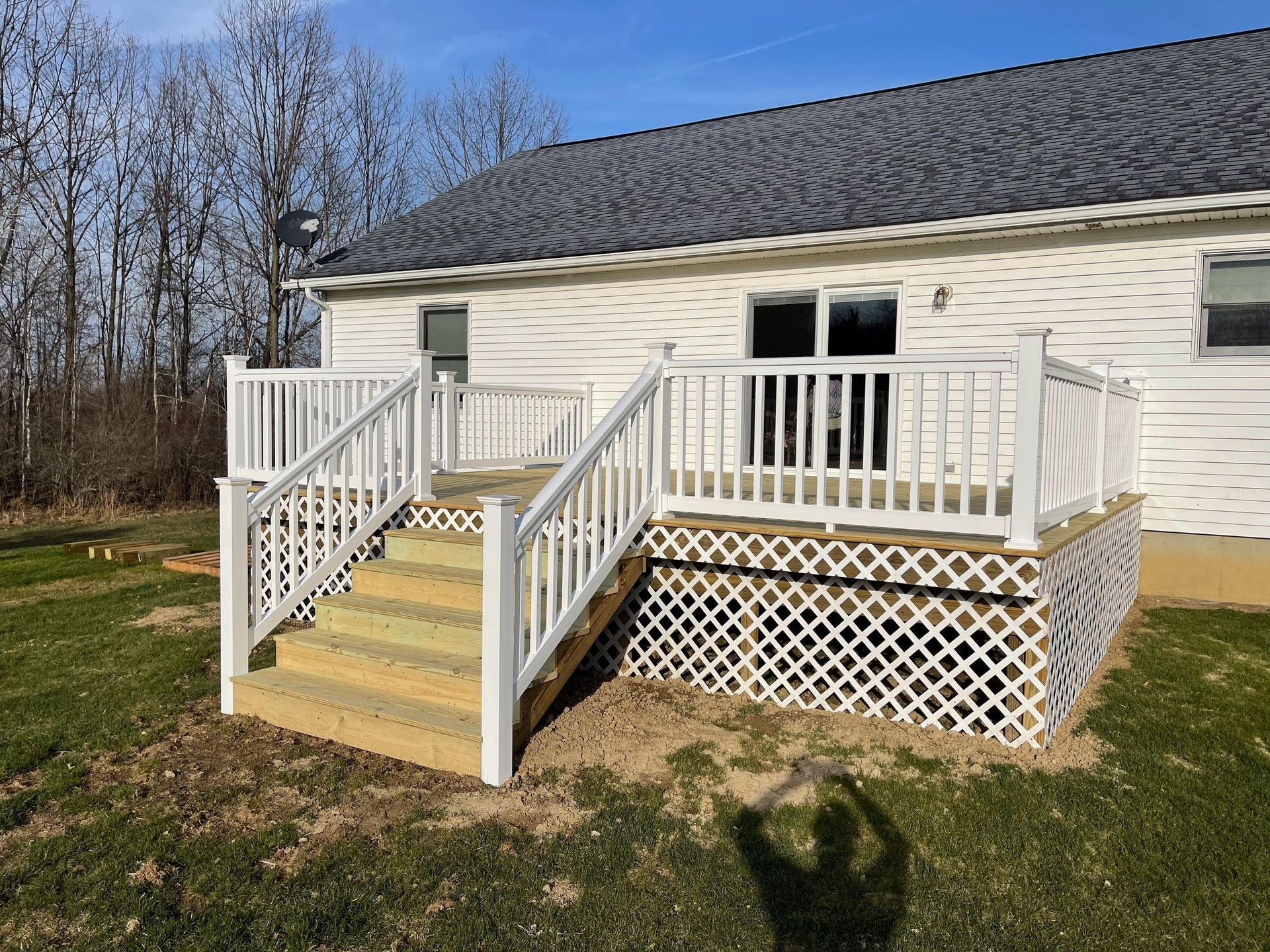 White deck with stairs, lattice skirting, and railing, attached to a white house.