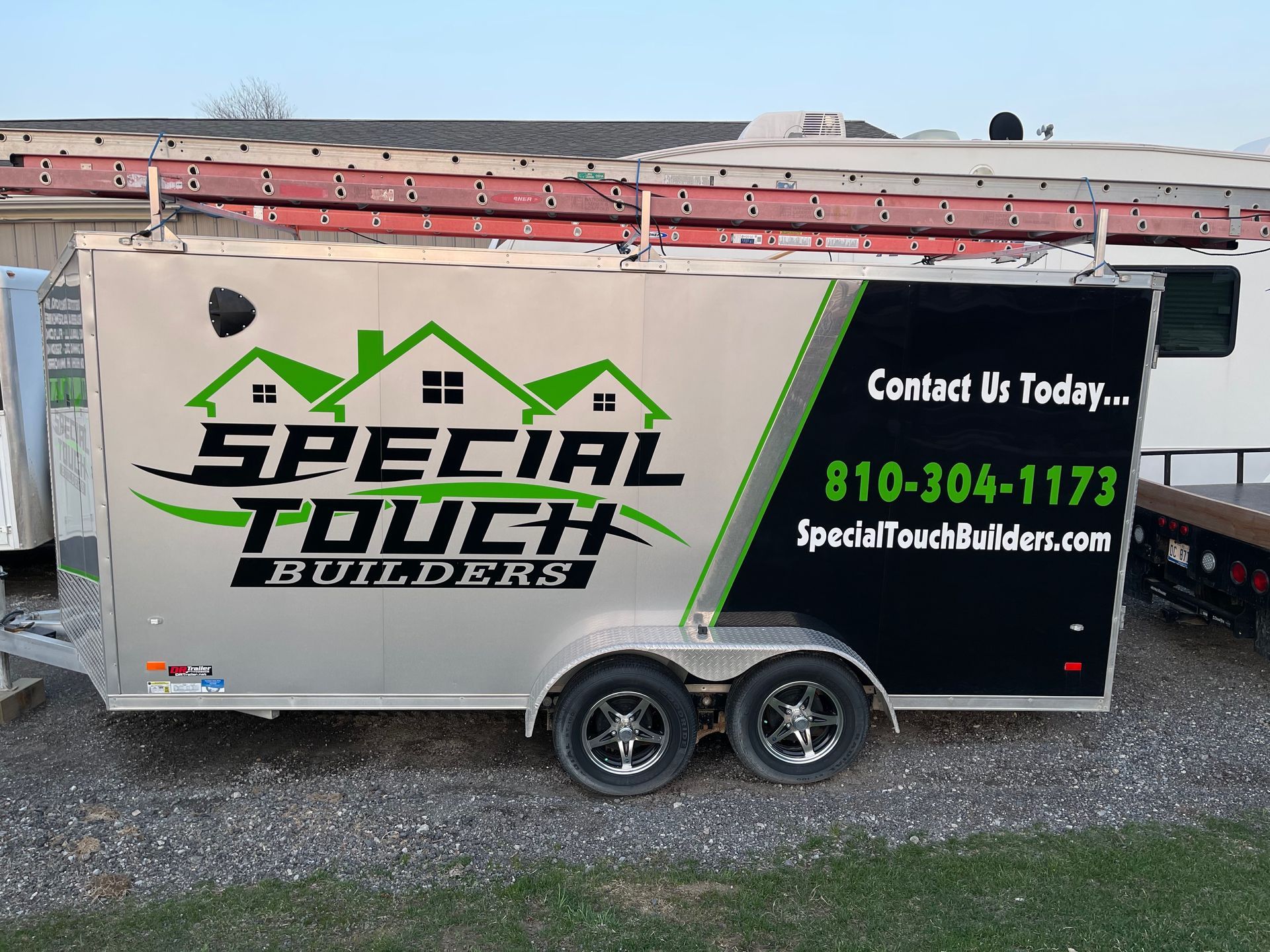 Silver trailer with logo, phone number, and website.